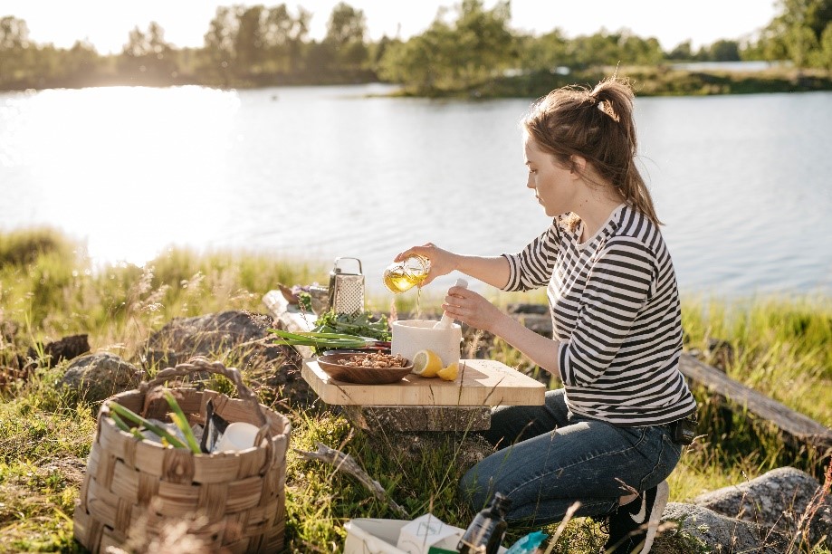 Woman cooking on the rocks in front of a lake.