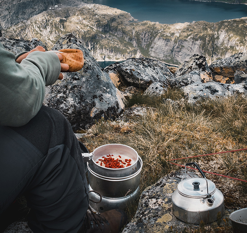 A man eating porridge for breakfast with a view over a lake in the mountains in Northern Norway